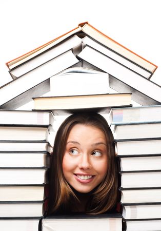 This is a photo of a house made out of books. There is a roof and walls. The center is open. A young woman smiling face is in the middle of the structure.