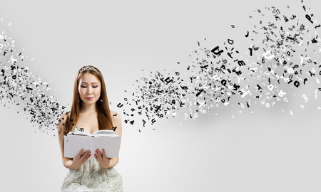 This is a photo of a young woman reading a book. She appears to be in deep concentration. Letters are pouring out of the books and surrounding her.
