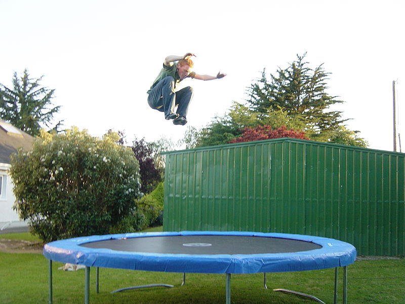 This is a young man jumping high in the air on a trampoline.