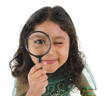 This is a photo of a young girl holding a magifying glass to her eye. It is meant to communicate that perspective matters in storytelling.