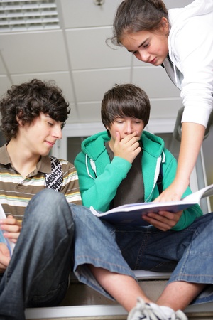 This is a picture of a teacher helping two students who are reading a text.