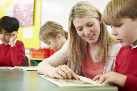 This is a picture of a female teacher helping a male student with his reading assignment. They appear to be finding success at this assignment.